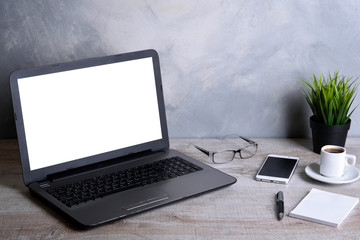  Laptop with blank screen for graphic display montage .Computer on wooden gray desk in office room. Mock up with plastic  plant