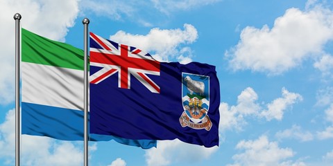 Sierra Leone and Falkland Islands flag waving in the wind against white cloudy blue sky together. Diplomacy concept, international relations.