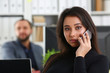 © H_Ko - young pretty brunette woman in office work with her boss hold smartphone in hands