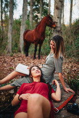 Wall Mural - Young women reading a book and taking photos in the forest