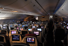 Interior Of A Jet Airplane On A Long International Flight With TV Screens On The Back Of Seats