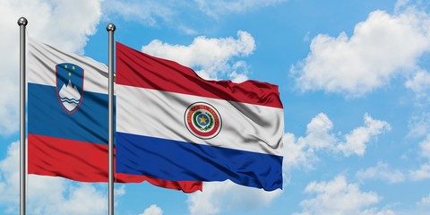 Slovenia and Paraguay flag waving in the wind against white cloudy blue sky together. Diplomacy concept, international relations.