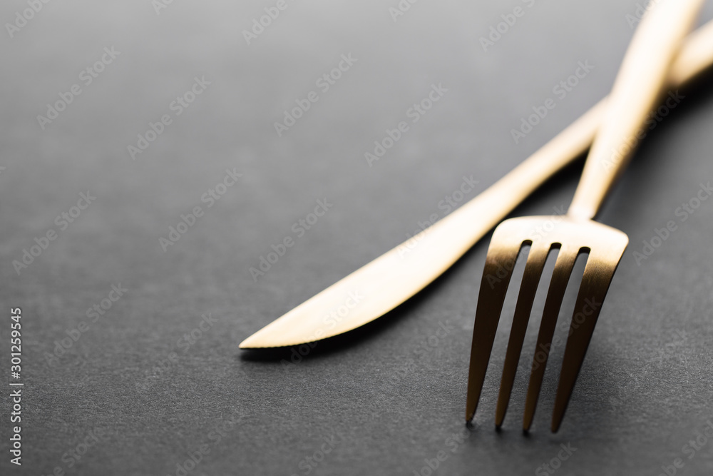 Gold cutlery set on black background - obrazy, fototapety, plakaty 