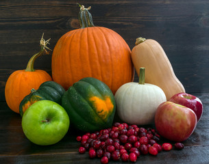  Rustic grouping of cranberries, apples, acorn squash, butternut squash, and pumpkins on a dark wood background