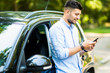 © F8  \ Suport Ukraine - Handsome young man standing and using the phone with his car.