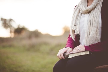 Closeup shot of a female sitting while holding the bible with a blurred background