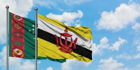 Turkmenistan and Brunei flag waving in the wind against white cloudy blue sky together. Diplomacy concept, international relations.