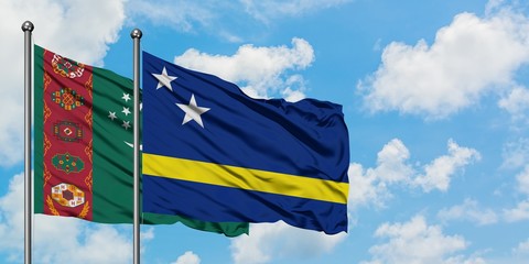 Turkmenistan and Curacao flag waving in the wind against white cloudy blue sky together. Diplomacy concept, international relations.