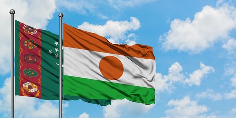 Turkmenistan and Niger flag waving in the wind against white cloudy blue sky together. Diplomacy concept, international relations.
