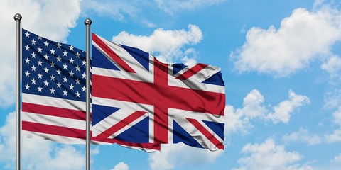 Wall Mural - United States and United Kingdom flag waving in the wind against white cloudy blue sky together. Diplomacy concept, international relations.