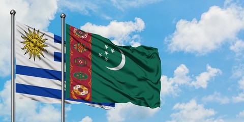 Uruguay and Turkmenistan flag waving in the wind against white cloudy blue sky together. Diplomacy concept, international relations.