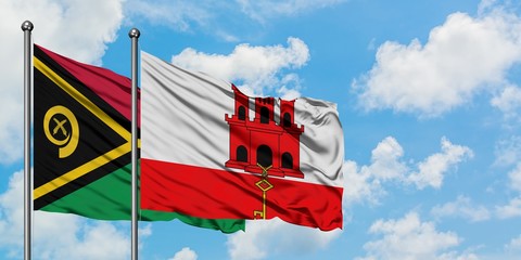 Vanuatu and Gibraltar flag waving in the wind against white cloudy blue sky together. Diplomacy concept, international relations.