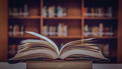 Poster - Stack of books in the library and blur bookshelf background