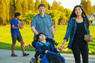 Father walking with family and disabled son at park