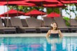 © siraphol - Portrait young asian woman relax smile happy around outdoor swimming pool in hotel resort with sea ocean view