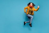 Fototapeta  - Full body photo of amazing lady jumping high running fast shopping discounts excited wear stylish windbreaker jeans scarf sweater isolated blue color background