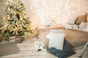 Wall Mural - Rustic bedroom interior decorated for Christmas. New Year's interior Scandinavian style bed with pillows. Textural light room of a farmer's house with a Christmas tree and a garland. Background for te