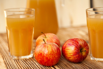 Ripe apples and freshly squeezed juice in glasses on a wooden table