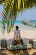 © allenkayaa - A young woman under a palm tree on the shore of the Gulf of Thailand. Woman in a hat looks at the sea