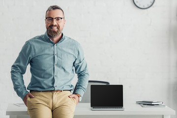 Wall Mural - handsome businessman sitting on table near laptop with copy space