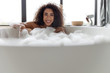 Cheerful Afro American lady taking bath at home