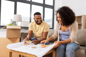 Wall Mural - accommodation, moving and real estate concept - happy african american couple with blueprint and color palettes at new home