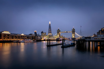Fototapete - Die Skyline von London am Abend: Tower Bridge und moderne Bürogebäude entlang der Themse