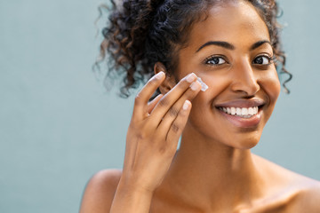 woman applying moisturizer on face