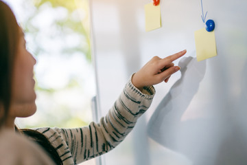 Business people looking, discussing and pointing finger at whiteboard in office