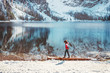 Colorful winter landscape with a girl walking along the mountain lake Braies,Dolomites.Young woman enjoys a walk on Lake Braies on a winter clear sunny day, Dolomites.Popular tourist spot in Italy