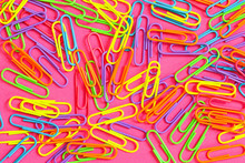 An Assortment Of Brightly Colored Neon Paperclips Against A Pink Background