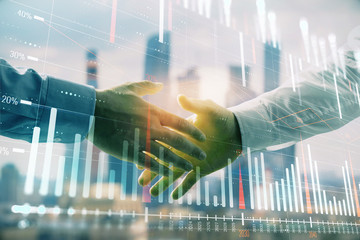 Double exposure of financial graph on cityscape background with two businessman handshake. Concept of stock market deal