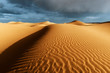 Sahara sand dunes with stormy, cloudy sky at Erg Lihoudi.