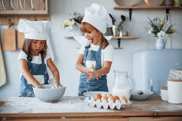 Wall Mural - Family kids in white chef uniform preparing food on the kitchen