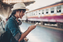 Asian Tourist Teenage Girl At Train Station Using Smartphone Map, Social Media Check-in, Or Buy Ticket Booking. Modern Travel App Technology, Lone Traveler, Summer Vacation Railroad Adventure Concept