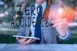 © Artur - Writing note showing Zero Accidents. Business concept for important strategy for preventing workplace accidents Female business person sitting by table holding mobile phone