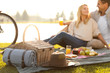 © New Africa - Happy young couple having picnic near lake, focus on wicker basket with blanket and hat