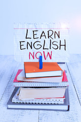 Poster - Conceptual hand writing showing Learn English Now. Concept meaning gain or acquire knowledge and skill of english language pile stacked books notebook pin color reminder white wooden