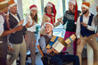 © luckybusiness - People celebrating winter holidays together at work. Happy business people in santa hat.