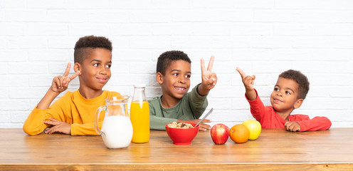 Wall Mural - African American brothers having breakfast and making victory gesture