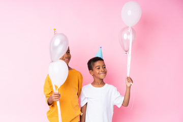 Poster - Two African American brothers holding balloons over isolated pink background