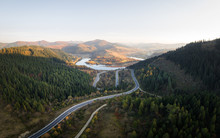 Aerial Drone View Over The Autumn Mountains With Mountain Road Serpentine, River And Forest. Landscape Photography