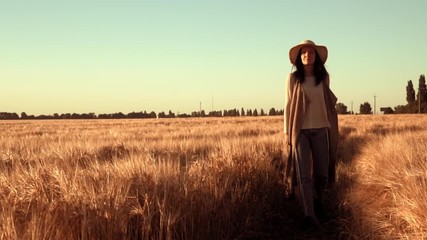 Poster - woman farmer wearing straw hat and jeans stroll across field ripened wheat rural landscape in autumn season