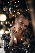 © irinaneva - Beautiful sexy blonde girl posing in a shiny dress. New Year's interior, garlands