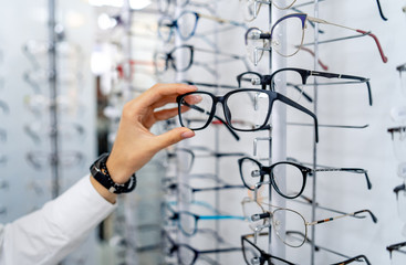 row of glasses at an opticians. eyeglasses shop. stand with glasses in the store of optics. woman ch