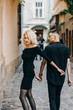 © Yuliia - Fashionable couple walking down the street holding hands. Exquisite blonde woman looking back