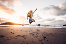 Happy Man Jumping At The Beach On A Sunset Background