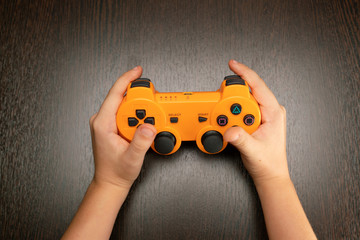 Children's hands hold the joystick from the game console