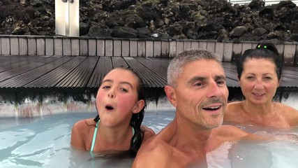 Canvas Print - Happy family of three people enjoying hot thermal pool in summer season. Slow motion