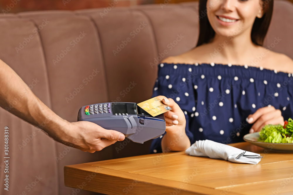 Woman paying bill in restaurant through terminal